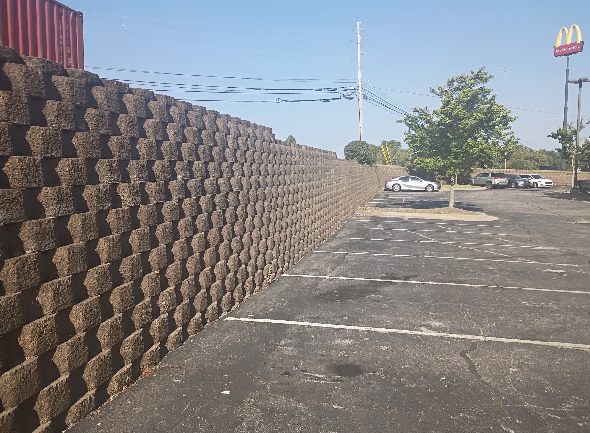 Long segmental block retaining wall running beside a commercial parking lot