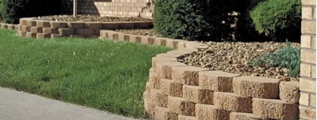 Curved tan block retaining walls wrapping planting beds along a driveway