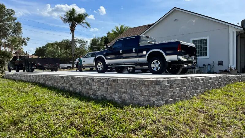 Block retaining wall carrying a raised driveway pad with a pickup truck parked on top