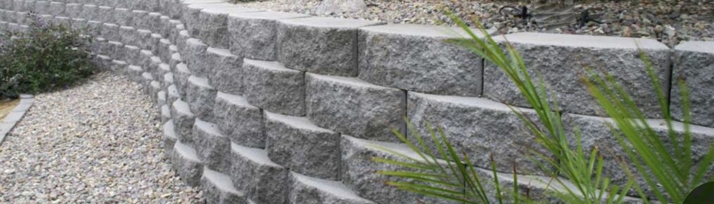 Gray split-face block retaining wall with a gravel path at its base